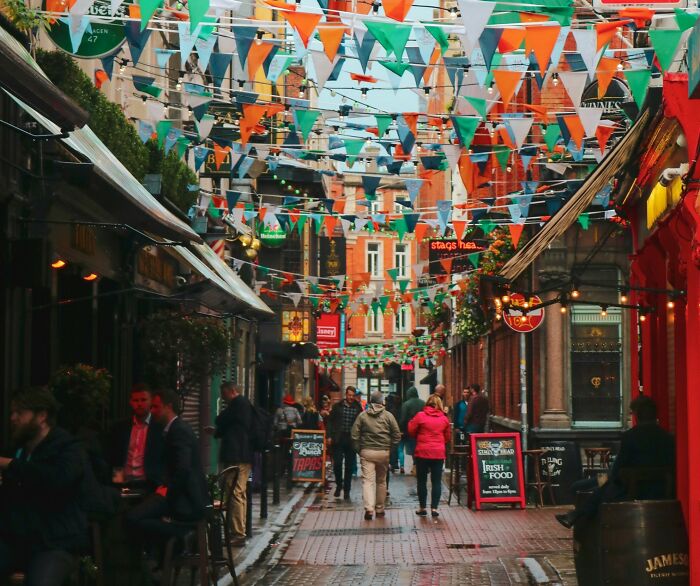 A lively European street decorated with flags and people walking, illustrating European netizens correcting common country facts.