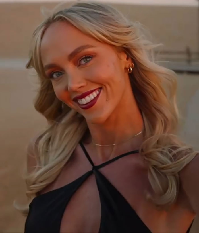 Blonde woman smiling outdoors in a black top, related to woman who slept with 583 men and assault allegations.