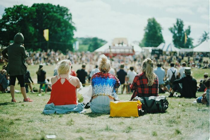 Three women sitting on grass at an outdoor event, highlighting awkward moments when nice guys turned creepy.
