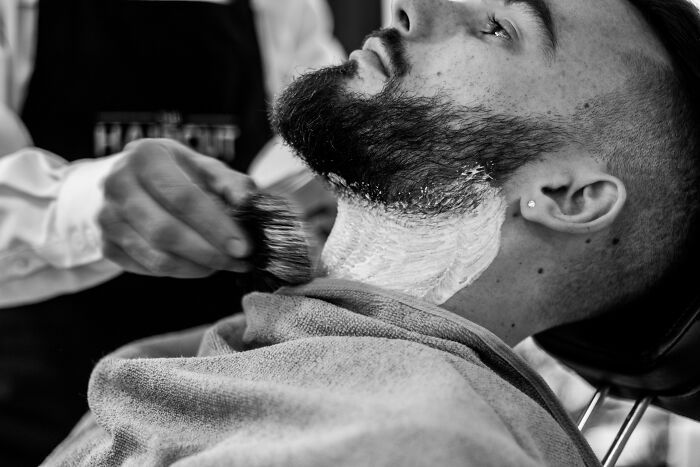 Man receiving a beard shave at a barber shop, illustrating relaxation and the famous paradox of choice and simplicity.