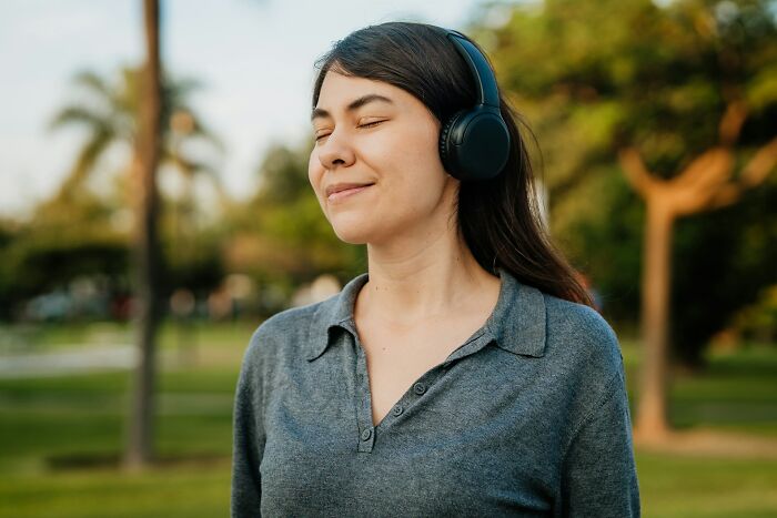 Young woman wearing headphones outdoors, enjoying music and relaxation with everyday items under 300 dollars improving life.