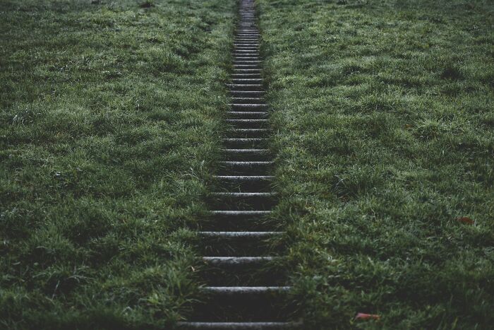 Stone steps leading upwards through a grassy area, symbolizing the journey of people falling for fictional things never real.