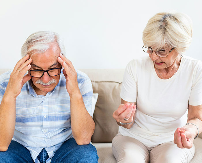 Older woman discussing therapy with a frustrated man on a couch, illustrating a Christian woman&rsquo;s disbelief in therapy.