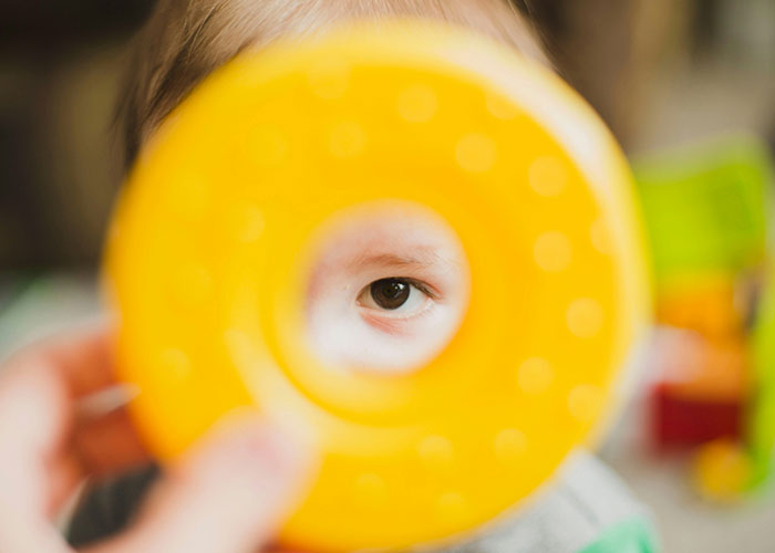 Child's eye seen through the center of a yellow toy, illustrating strange things autopsy doctors have discovered on the job.