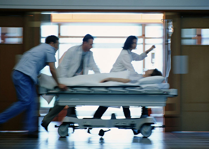 Medical staff rushing patient on a hospital stretcher, related to strange things autopsy doctors have discovered on the job.