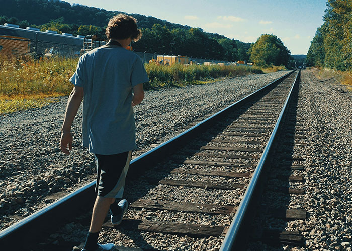 Person walking alone on railroad tracks in a rural area, evoking themes related to strange things autopsy doctors have discovered.