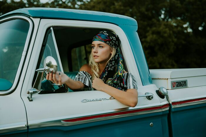 Woman living alone looks thoughtfully out of a vintage blue truck window, showcasing uncommon hacks for independence and confidence.