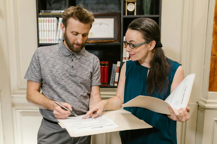Man and woman reviewing documents in office setting, illustrating a husband filing for divorce amid baby gender dispute.