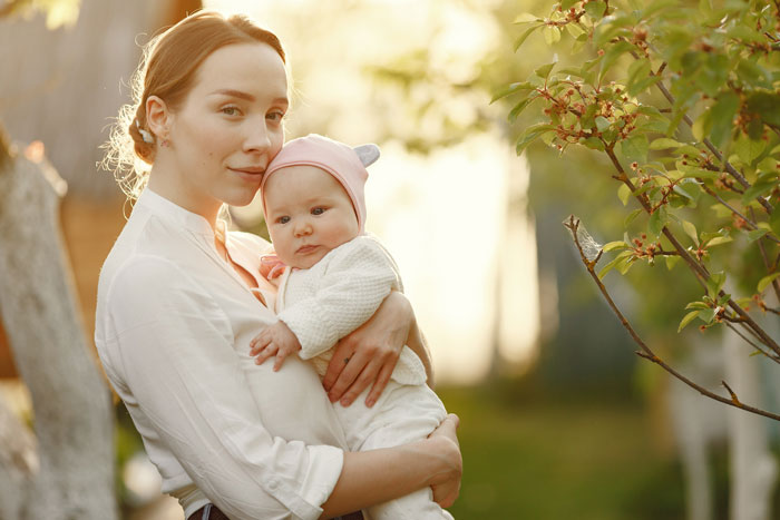 Young mother holding baby outdoors at sunset, reflecting MIL convinced pregnant DIL manipulated baby&rsquo;s gender issue.