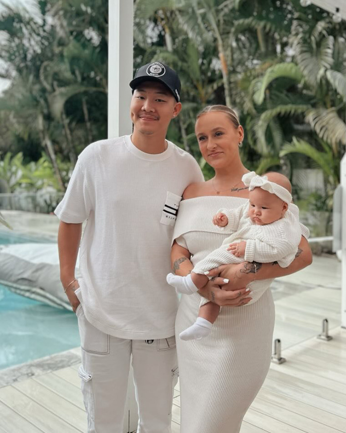 Parents with their 5-month-old baby dressed in white near an outdoor pool, reflecting a 5-month-old baby rushed to hospital scenario.