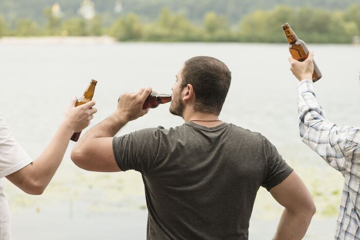 Three men drinking beer by a lake, illustrating some bad things people face in life related to alcohol use.