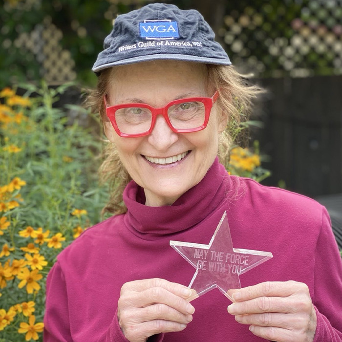 Beloved &rsquo;90s star and Rain Man co-star smiling outdoors, wearing a WGA hat and holding a star-shaped award.