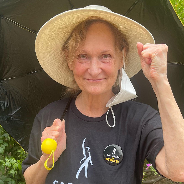 Beloved &rsquo;90s star and Rain Man co-star wearing a hat and a strike button, raising fist outdoors.