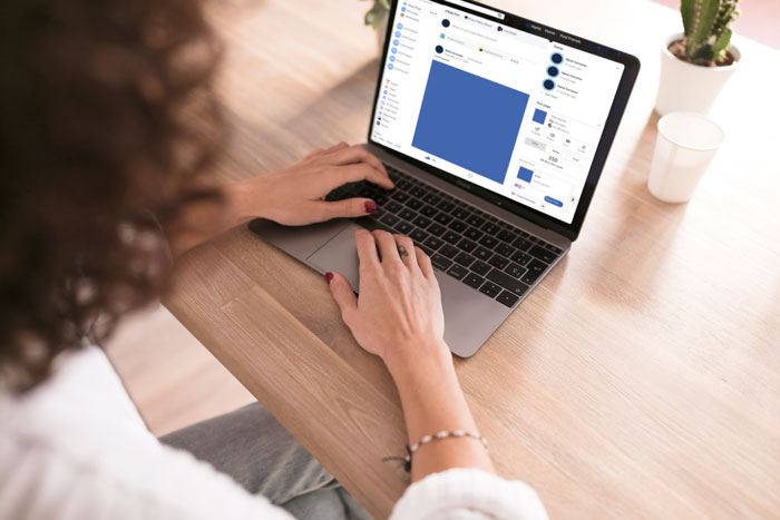 Person using laptop at wooden desk, browsing social media about best friend drama with secret babies and memorial plans.