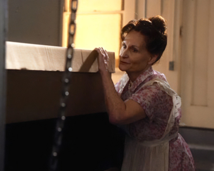 Beloved &rsquo;90s star and Tom Cruise&rsquo;s Rain Man co-star wearing floral dress and apron, leaning on a table indoors.