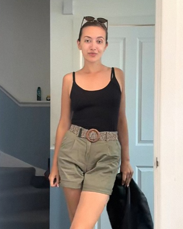 Young woman standing indoors in casual shorts and tank top, illustrating weight loss on Mounjaro with possible side effects.