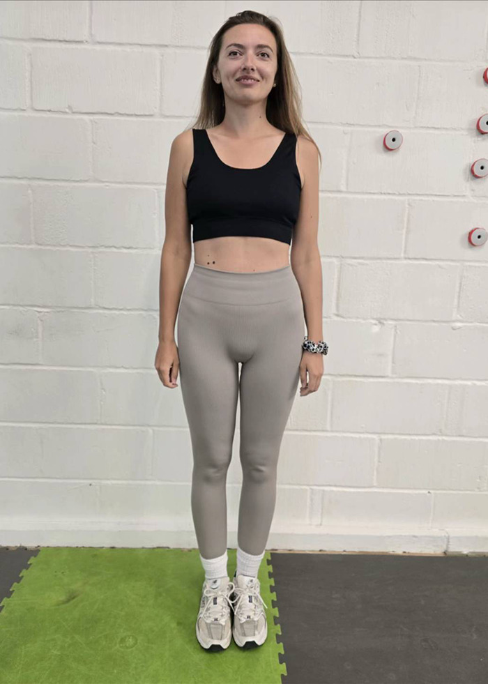 Slim woman standing in workout clothes against white wall, illustrating weight loss and Mounjaro side effects experience.