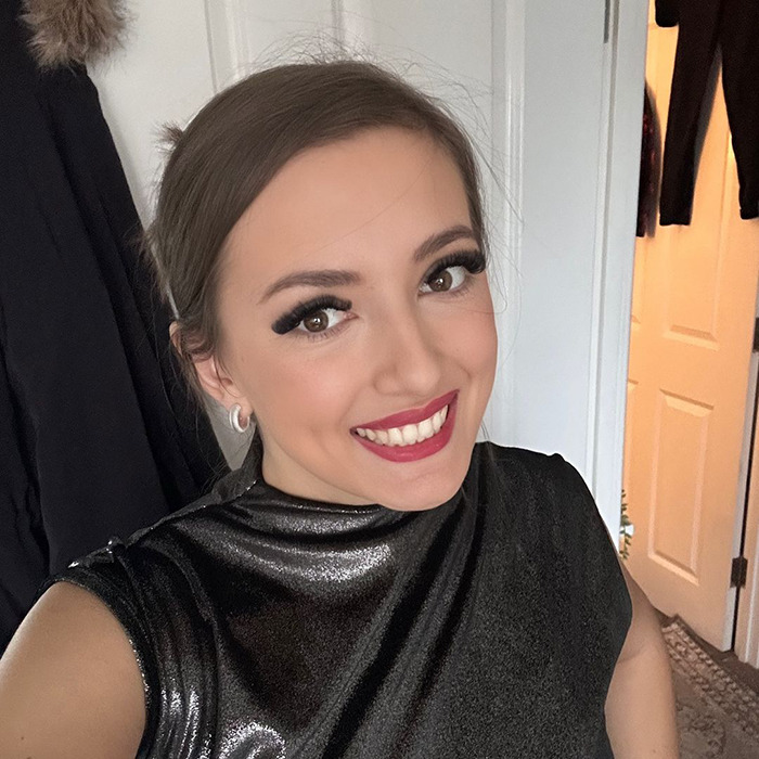 Smiling woman in a black shiny top sharing her experience with Mounjaro weight loss and side effects.