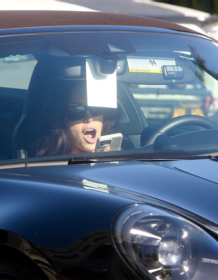 Woman allegedly infringing law again using phone while driving her black Porsche with sunglasses on inside the car.