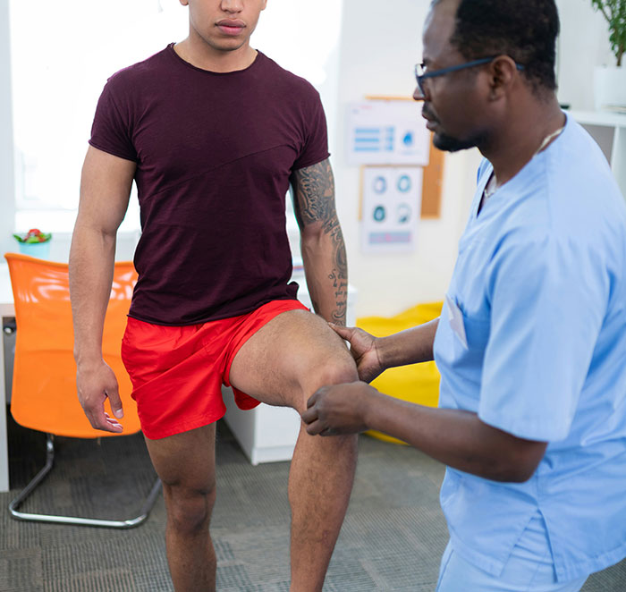 Patient in red shorts receiving physical therapy for leg, highlighting one of the biggest flaws of the human body.