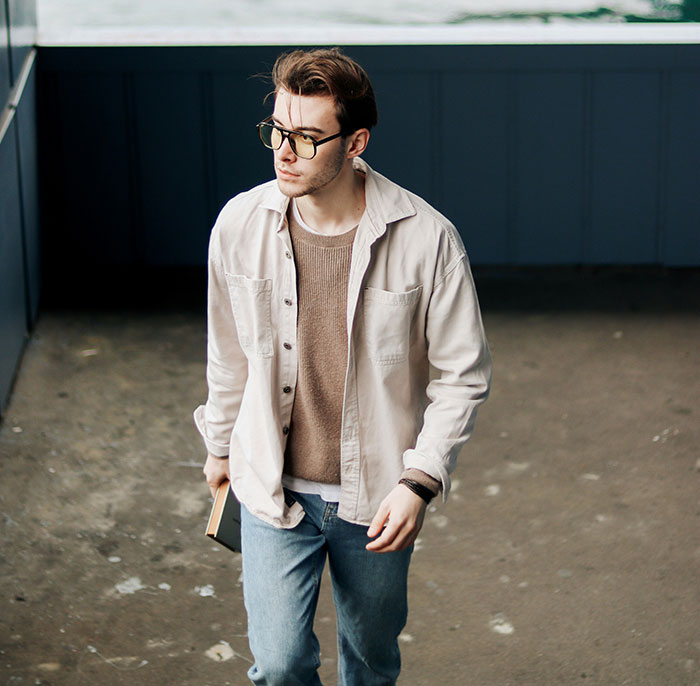 Young man wearing glasses and casual clothes holding a book, symbolizing flaws of the human body in everyday life.