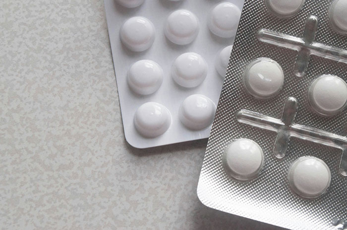 Blister packs of white pills on a light surface representing a potential scandal in human history related to medicine.