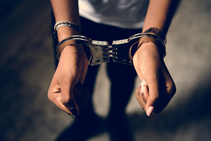 Person in handcuffs with wrists secured, symbolizing scandals in human history related to crime and justice.