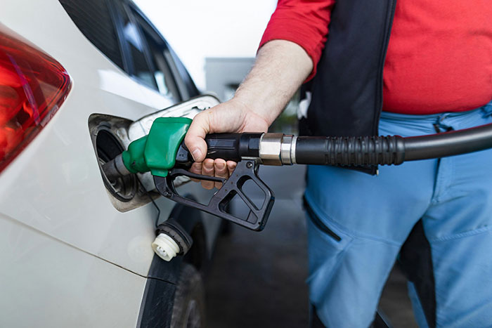 Person fueling a car with a green gas pump, illustrating a possible scandal in human history involving fuel or energy.