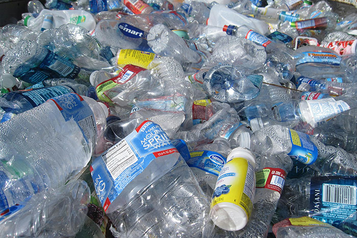 A large pile of discarded plastic bottles and containers representing plastic pollution as a major human history scandal.