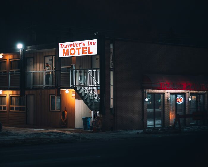 Traveller's Inn motel at night with a person on the balcony, illustrating stories of people ruining their entire life.