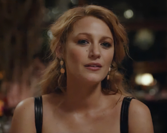 Blake Lively looking thoughtful in a dimly lit setting amid lawsuit news involving Justin Baldoni.
