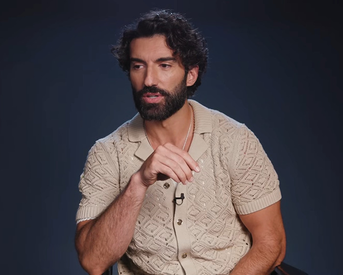 Man with dark curly hair and beard wearing beige patterned short sleeve shirt speaking in a studio setting involving Blake Lively lawsuit