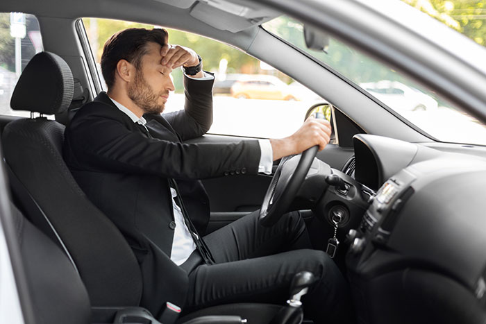 Man in a suit sitting in car looking stressed during commute with only 30 minutes of work left after break and no overtime. Man in a suit sitting in car looking stressed during commute with only 30 minutes of work left after break and no overtime.