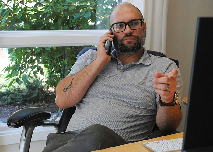 Boss making lunch break meetings, sitting at desk by window, talking on phone, wearing glasses and grey polo shirt. Boss making lunch break meetings, sitting at desk by window, talking on phone, wearing glasses and grey polo shirt.
