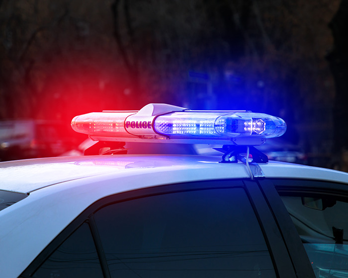 Police car with flashing red and blue lights responding to an incident involving a boy in a viral scarf challenge.