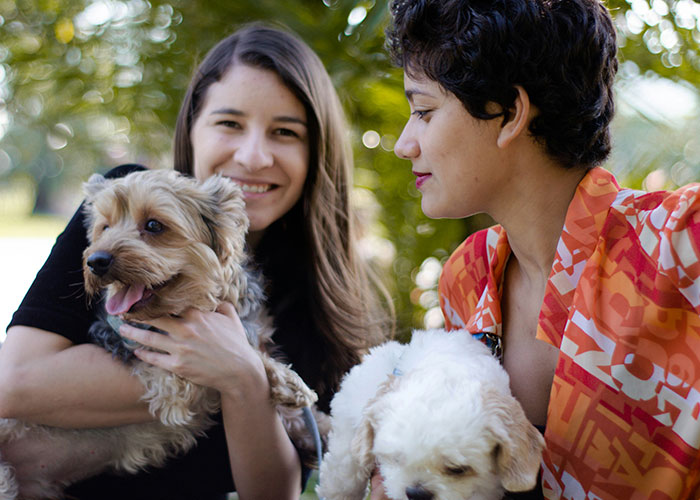 Two women holding dogs outdoors, illustrating moments where people broke guy or girl code for better choices.