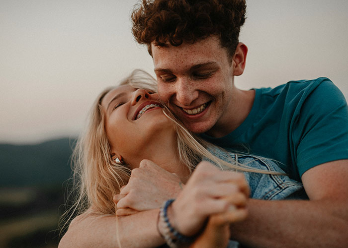 A young couple laughing and hugging outdoors, illustrating moments when people broke guy or girl code for a better choice.
