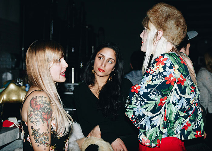 Three women in a social setting, engaged in a serious conversation about breaking guy or girl code choices.