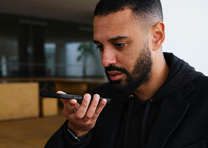 Man speaking into smartphone voice recorder, illustrating moments people broke guy or girl code for a better choice