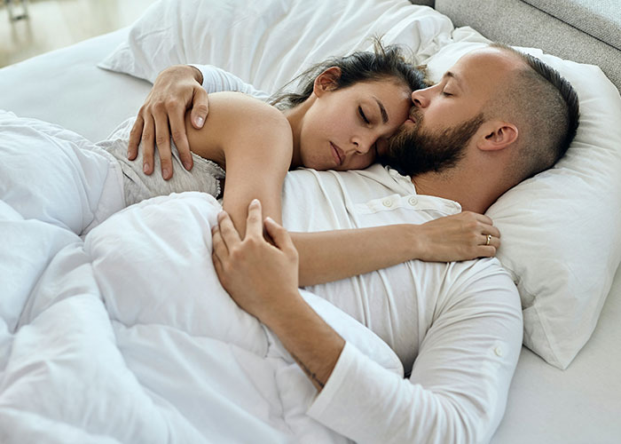 Couple breaking guy or girl code, embracing closely in bed showing intimacy and emotional connection.