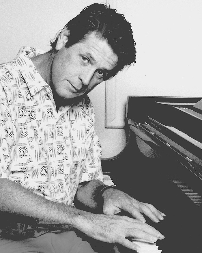 Legendary Beach Boys co-founder and musical genius playing piano in a black and white photo.