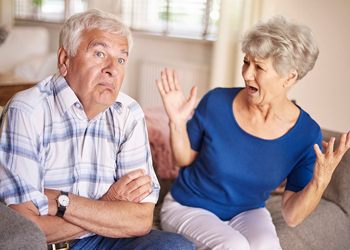 Older couple having a heated argument at home, showing signs of divorce and wedding drama witnessed by man.