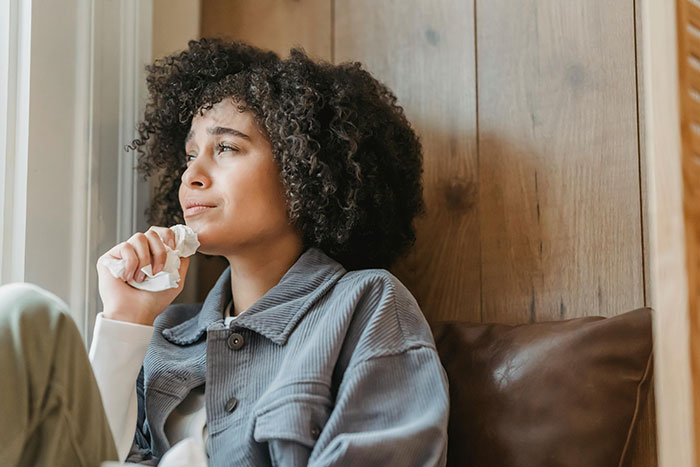 Young woman with curly hair crying while sitting alone, capturing the bride&rsquo;s dream bachelorette turning into a lonely cry-fest.