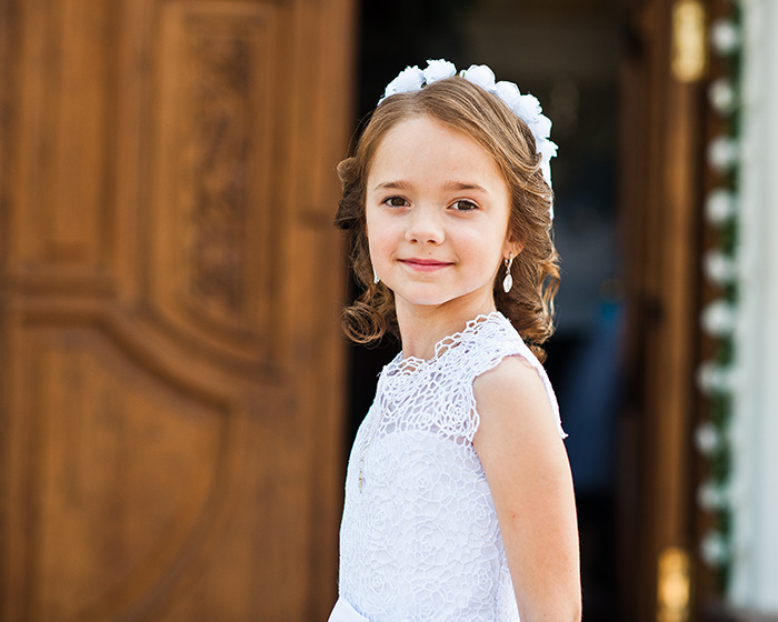 Young girl in white dress and floral headband standing near wooden door, related to Disneyland wedding news case.