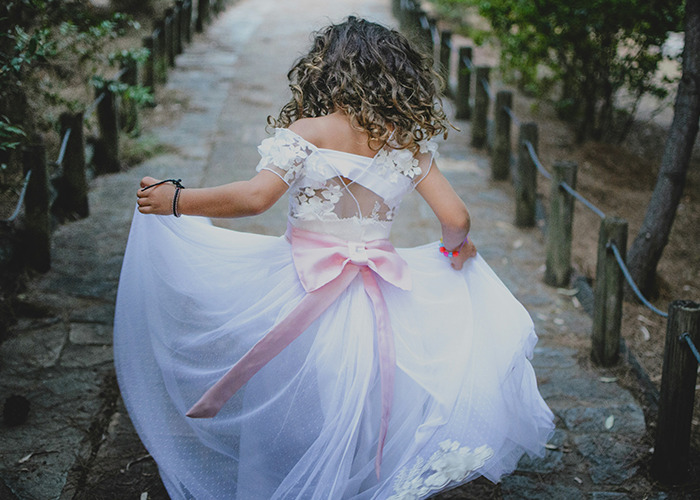 Young girl in a white dress with a pink bow walking on a stone path, relating to Disneyland wedding arrest news.