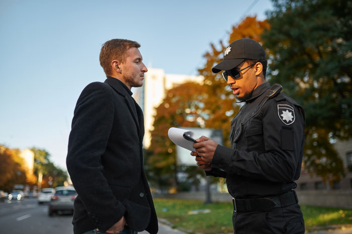 Man talking to police officer outside during daytime, illustrating backlash after calling cops on family using his pool.