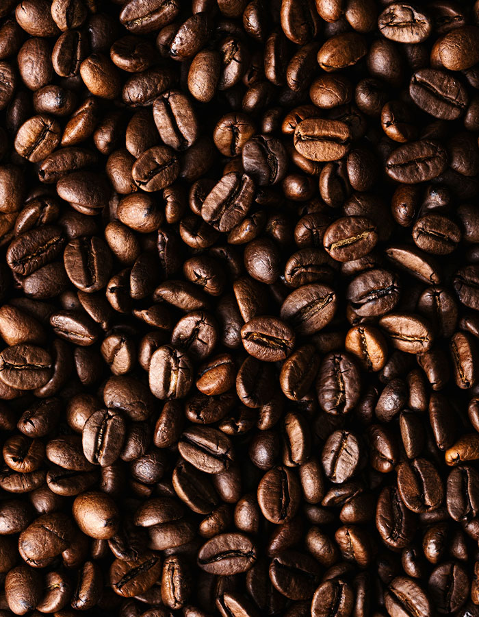 Close-up of dark roasted coffee beans, highlighting caffeine as the main focus related to excessive consumption risks.