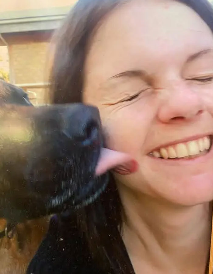 Australian woman smiling as dog licks her cheek outdoors, illustrating a personal moment before caffeine overdose news.
