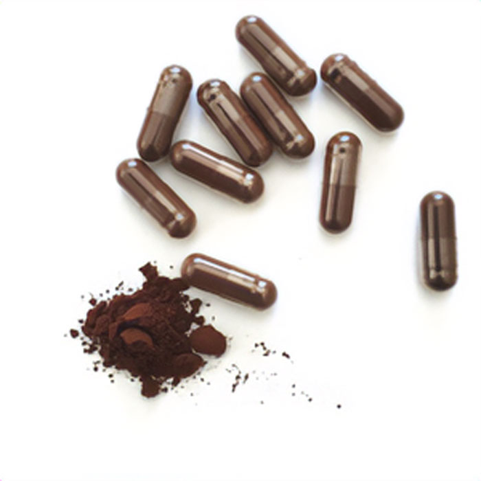 Brown caffeine supplement capsules scattered beside a small pile of loose caffeine powder on a white background.
