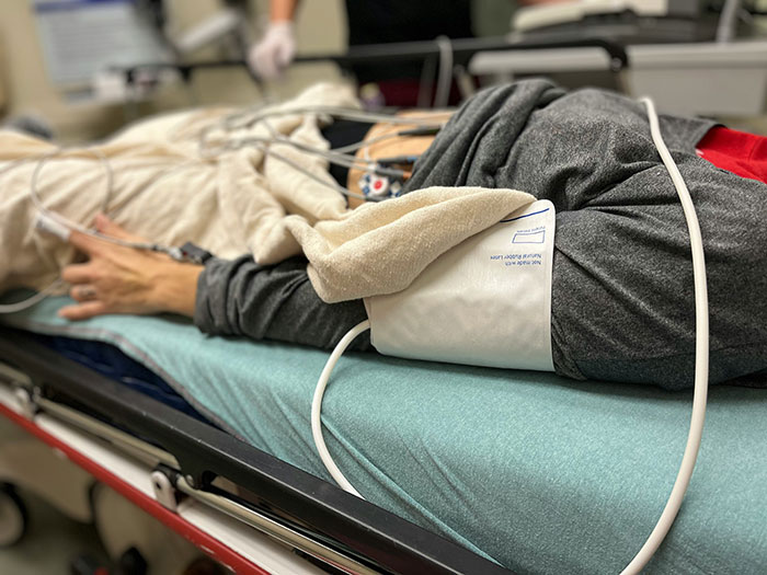 Patient lying on hospital bed with medical monitoring devices and blood pressure cuff after a major accident. Patient lying on hospital bed with medical monitoring devices and blood pressure cuff after a major accident.
